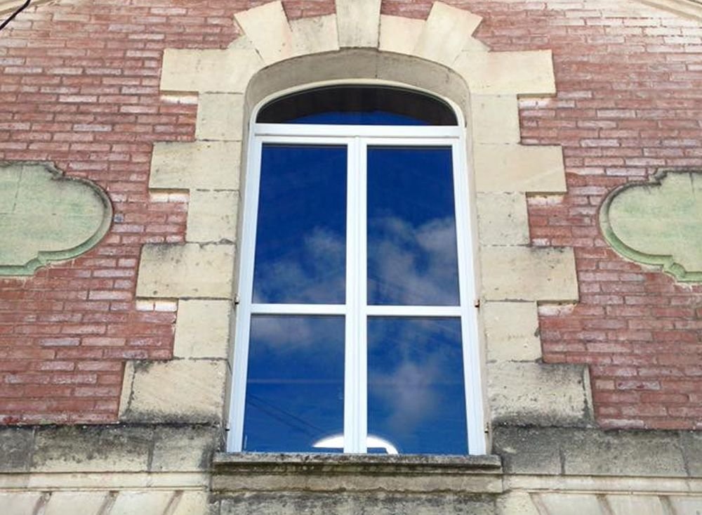 Fenêtre cintrée posée dans une façade de brique et de pierre